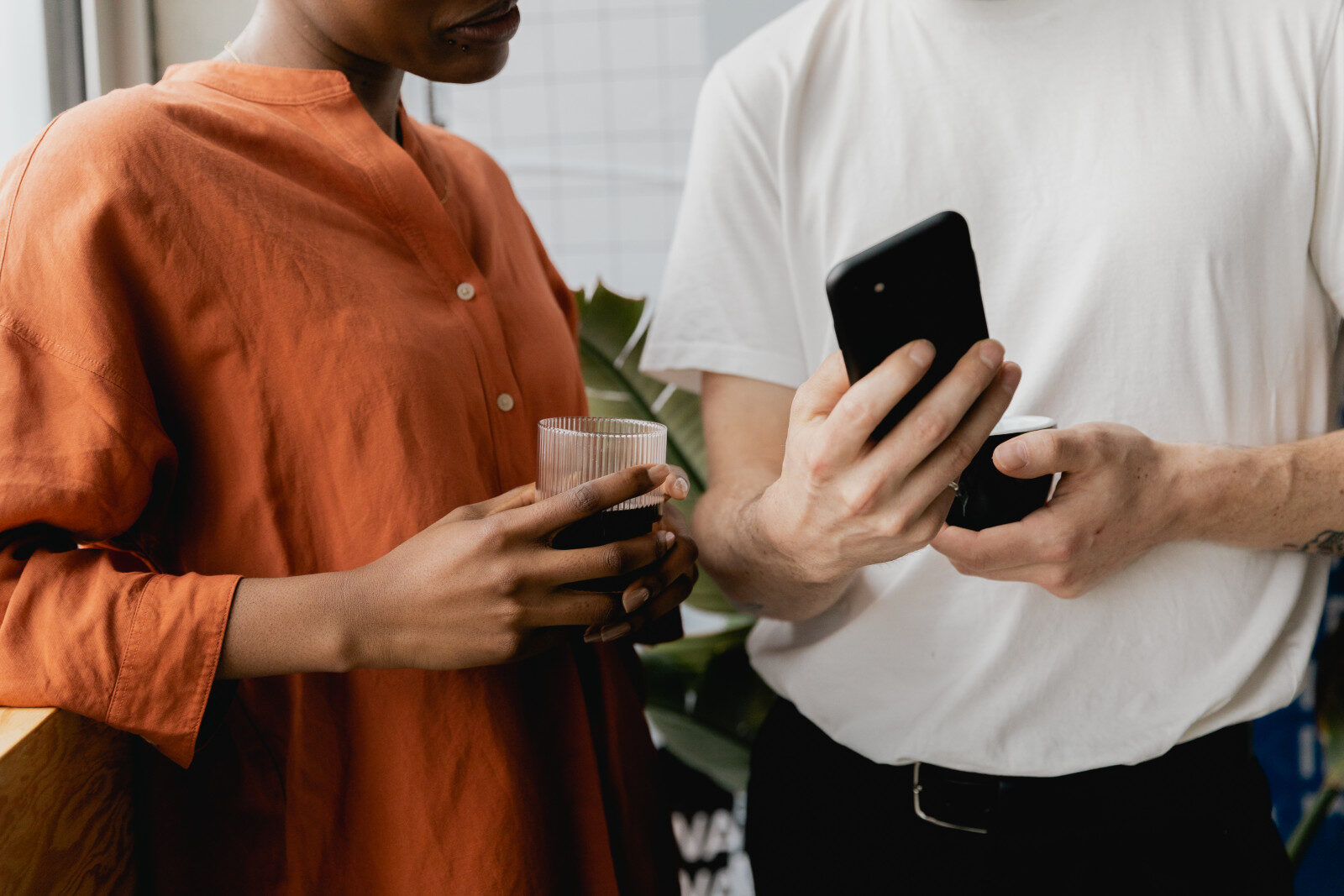 Two people at a launch event holding cold brew glasses while comparing something on a phone