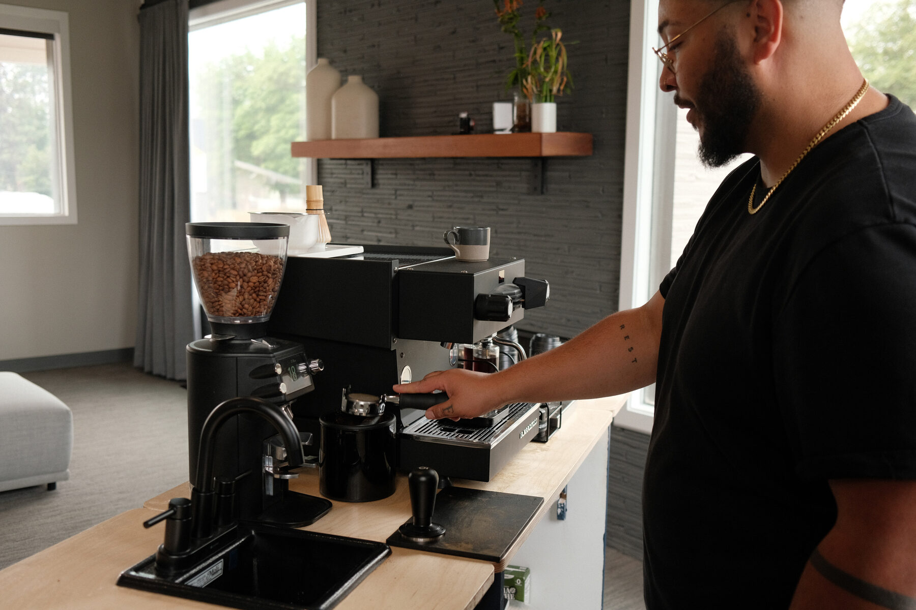 Nathan reaching across the bar mid-service, grinder and machine set up on the counter