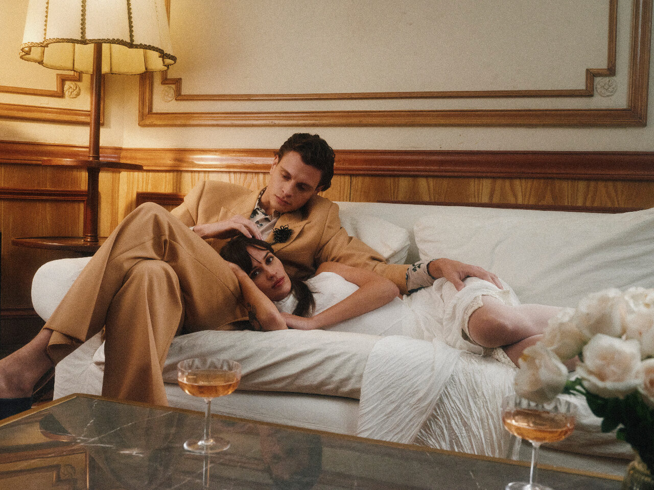 A couple resting together in a warm, wood-panelled suite before the reception